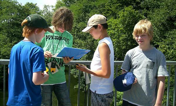 4 Jugendliche stehen auf einer Brücke und nutzen GPS.