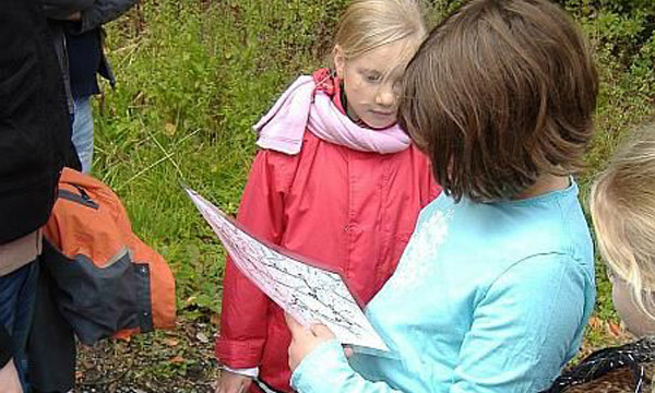 Ein Gruppe Kinder startet eine Fotoschatz-Suche und liest die Schatzkarte.
