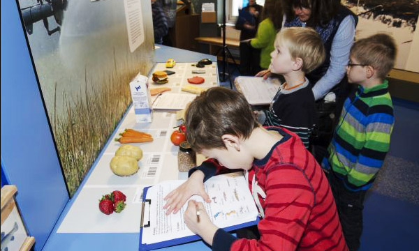 Ein Gruppe Kinder wird im Liz in der Umweltbildungs-Ausstellung angeleitet Obst und Gemüse zu bestimmen.